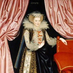 Painting of (probably) Elizabeth Cary, Viscountess Falkland, by William Larkin.  She is wearing court dress, elaborate from her lace head-dress and huge lace collar to her heavily decorated shoes. She stands framed between pink curtains, beside a red and gilt chair with cushion, on a figured carpet. Her fair hair is stiffly styled away from her face. She wears a blue velvet mantle with embroidered borders over a bodice tied with ribbons: that and her sleeves and petticoat are also embroidered. Kenwood House