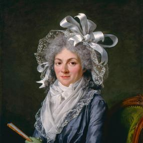 Painting of Stéphanie-Félicité de Genlis by Adélaïde Labille-Guiard, 1790. She is seated in a green upholstered chair, her arms folded on her lap, one hand holding a small fan. She wears light green gloves, a blue silk dress with layers of neckerchiefs and a lacy bow at the neck. Her curly, powdered hair is partly covered by a lace bonnet with huge silvery bows.