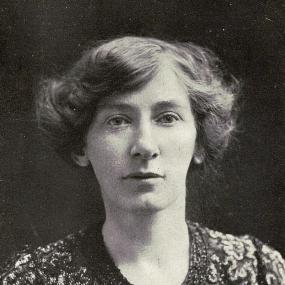 Black and white photograph of Cicely Hamilton, shown from the shoulders up. She is wearing a shimmery beaded jacket, and her hair is jaw-length and wavy.