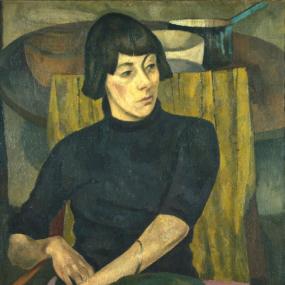 Painting of Nina Hamnett by Roger Fry, 1917. She is seated in a wooden chair with a yellow back and pink seat, wearing a long grey-green skirt and a black turtleneck whose sleeves leave her slender forearms bare. Her dark hair is short, with a fringe. Courtauld Institute.