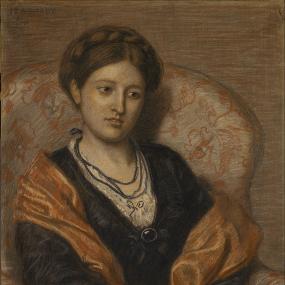 Portrait of Iza Duffus Hardy by Ford Madox Ford, 1872. She sits in an upholstered armchair, wearing a black dress with lace at wrists and neckline (finished with a black brooch), a gold-coloured shawl, and several strings of blue beads. Her hair is plaited and forms a crown around her head. Her fingers are interlaced, and she looks modestly down, away from the viewer.