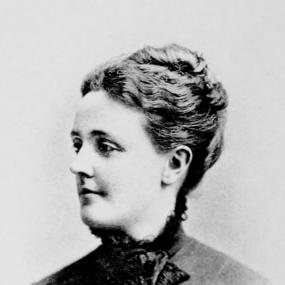 Black and white, head-and-shoulders photograph of Sarah Orne Jewett from her Tales of New England, 1894 edition. She is in semi-profile, wearing a high-necked buttoned jacket and a short scarf. Her dark, wavy hair is up in a bun.