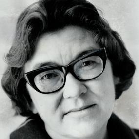 Black-and-white portrait photo of Margaret Laurence. She is wearing thick, dark rimmed glasses and has short hair. 