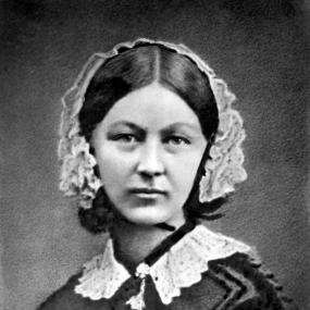 Black and white, head-and-shoulders photograph of the young Florence Nightingale. She is wearing a simple black dress with lace collar and lace cap, and looking directly into the camera.