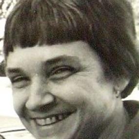 Black and white head-shot of Adrienne Rich. She has jaw-length hair with short bangs, and she wears a collared shirt.