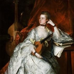 Photograph of a painting of Ann Thicknesse by Thomas Gainsborough, 1760, seated against the backdrop of a red curtain, with her arm resting on a small wooden table piled with books and sheet music. She is wearing a long voluptuous silver dress with a pattern  of swirls stitched onto it, lace trimmed sleeves, and soft yellow bows tied around the sleeves and waist. She has dark ribbons tied around her neck and wrist, dark circular earrings, and gold coloured shoes with small heals and buckles. She has a mando