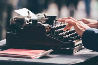 photo of hands typing on an old typewriter