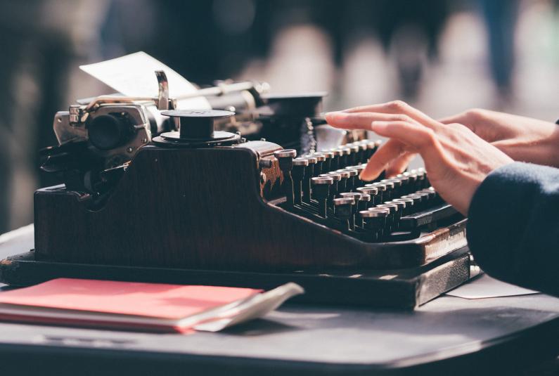 Hands typing on a vintage typewriter