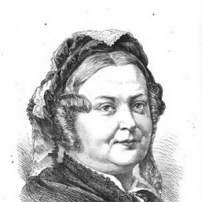 Black and white portrait of Clara Balfour. She is wearing a dark dress with thin white collar. Her hair, smooth in front with a middle parting, is piled up under a lace cap and arranged in sausage ringlets around her face.