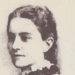 Black and white photograph of Frances Colenso. She is in semi-profile, looking to her left. Her hair is pulled back from her face, and she wears a white shirt with a dark ruffled fabric around her neck.