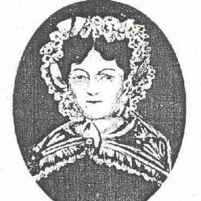 Photograph of a portrait of Anne Devlin, shown from the shoulders up. The portrait is contained within a dark oval set against a white background, and white negative space is used to indicate her features and clothing. She is wearing a shawl that is closed by a button in the center, and a frilly bonnet frames her face.