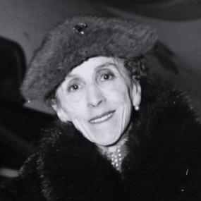 Black and white photograph of Isak Dinesen. She is shown from the shoulders up, and she wears a fur stole and fur hat, with pearl earrings.