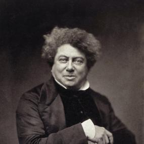 Half-length photograph of Alexandre Dumas the elder, November 1855, full-face, with clasped hands and a jovial half-smile.