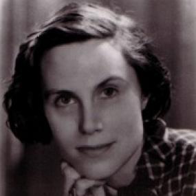 Black and white head-shot of Margiad Evans. Her head is resting on a hand, she has dark jaw-length hair, and she is wearing a checked jacket with a short scarf tied around her neck.