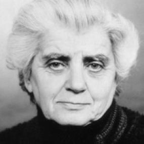 Black and white photograph of Karen Gershon, shown from the shoulders up. She is wearing a dark turtle neck and her hair is short, white, and wavy.