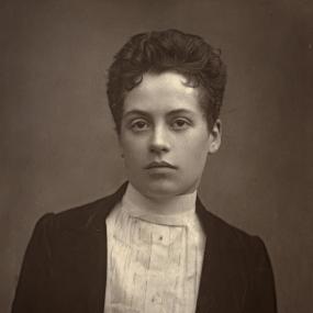 Black-and-white portrait photo of Clotilde Graves published in an 1888 issue of The Theatre, A Monthly Review. Looking directly at the camer,
            she is wearing a white blouse with a high collar and a velvet blazer. Her hair is wavy and cut very short. 