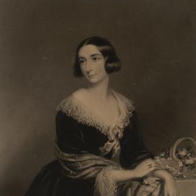 Sepia reproduction of a painting of Charlotte Guest by William Walker, 1852. Her smooth, dark hair is parted in the middle and coiled over her ears; she wears a dark dress with a deep V neck and a lace collar with a bow, a lacy shawl, and a ring on each hand. To the right  is a basket full of roses and other flowers. National Library of Wales.