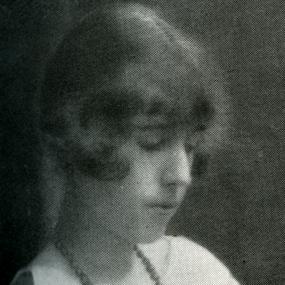 Black-and-white close-up photo of Georgette Heyer. Looking down, she wears a beaded necklace and her hair is bobbed. 