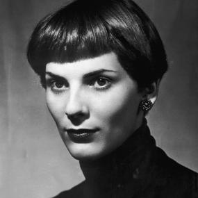 Black-and-white protrait photo of Elizabeth Jane Howard looking off-camera, circa 1956. She wears a dark turtleneck, beaded stud earrings, and
            has short hair that falls above her ear and is cut in bangs.