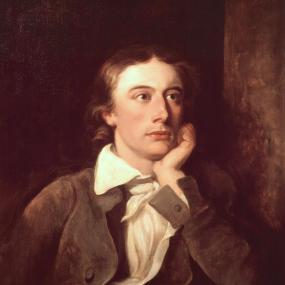 Painting of John Keats by William Hilton after Joseph Severn. Keats is seated with an open book in front of him, his chin on his hand, gazing into the distance. National Portrait Gallery.