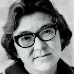 Black-and-white portrait photo of Margaret Laurence. She is wearing thick, dark rimmed glasses and has short hair. 