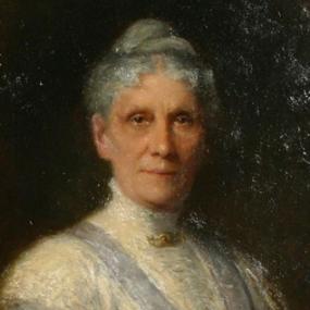 Photograph of a painting of Anna Leonowens by Robert Harris, about 1905. She is shown from the shoulders up, wearing a deeply V-necked grey dress with a high-collared white blouse under it. She has a green shawl wrapped around her and a gold pin at her neck, and her grey hair is pulled into a bun on top of her head.