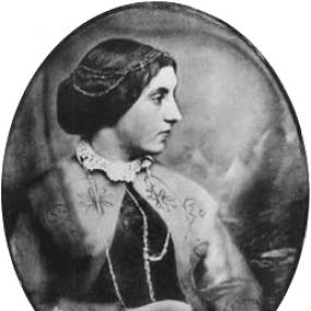 Black and white photograph of an oval painting of Jane Loudon, shown from the waist up. She is wearing a simple dress with dark bodice and light skirt,  a light cape patterned with flowers, and a lace collar. Slender chains lie around her neck and in her dark, neatly piled hair.