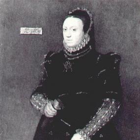 Black and white photograph of a painting of Lady Jane Lumley by Sieuwert van der Meulen, 1563, companion piece to a portrait of her husband. She stands in formal pose, wearing a long dark skirt and bodice with embroidered decoration. Her tight sleeves are puffed at the shoulders and the gold under-sleeves have small slashes. She has two rows of blue stones below a small ruff, and a circlet head ornament. In one hand she holds a pomander, in the other what might be the household purse.A small label is not le