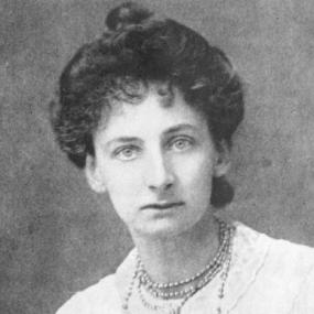 Black and white photograph of Constance Lytton, shown from the shoulders up. She is wearing a white dress and a beaded necklace, and her dark hair is pulled into a dark bun on the top of her head.