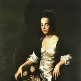 Photograph of a three-quarter-length painting of Judith Sargent Murray by John Singleton Copley. Her pale skin and white satin dress contrast strongly with her her black shawl and dark background. She is seated, looking directly at the viewer though her body is turned a little away. Her right knee is raised; her elbows rest on the arms of her chair, and her right hand holds a basket of flowers. Her dark hair is pulled back and ornamented with a ribbon.