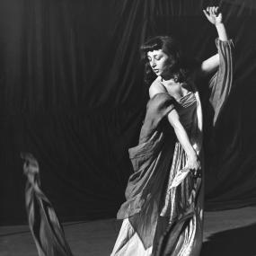 Black-and-white photo of Bernice Rubens looking off-camera as she performs the Dance of the Seven Veils as the eponymous heroine in Oscar
            Wilde's play Salome, 1947.