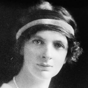 Black and white photograph of Lady Margaret Sackville, shown from the shoulders up, wearing a light dress and a pearl necklace, with a scarf tied around her dark, curly, jaw-length hair.