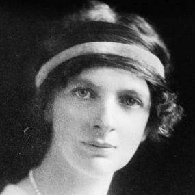 Black and white photograph of Lady Margaret Sackville, shown from the shoulders up, wearing a light dress and a pearl necklace, with a scarf tied around her dark, curly, jaw-length hair.