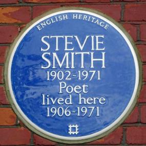 Photograph of a circular blue English Heritage plaque in the brick wall of Smith's "house of female habitation" in Palmers Green. It reads: "Stevie Smith, 1902-1971, Poet lived here 1906-1971."