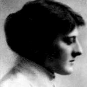 Black and white photograph of Mary Webb, shown in profile, from the shoulders up. She is wearing a simple light dress with a high collar and her dark hair is pulled back into a bun.