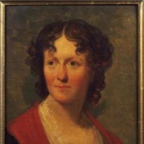 Portrait of Frances Wright by Henry Inman, 1824. She is looking to the left, plainly dressed in black with a red and white scarves, her brown, curly, shoulder-length hair parted in the middle.