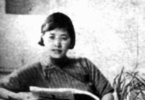 Somewhat blurry black and white photograph of Shuhua Ling, leaning back in a chair, holding an open book with large pages. Her hair is straight, jaw-length, and brushed back; she is wearing a pleated dress with a high neck.