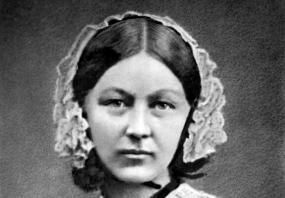 Black and white, head-and-shoulders photograph of the young Florence Nightingale. She is wearing a simple black dress with lace collar and lace cap, and looking directly into the camera.